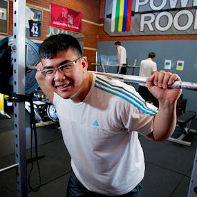 Asian man lifting weights in a gym 