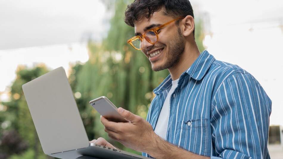 A man sat outdoors with a laptop