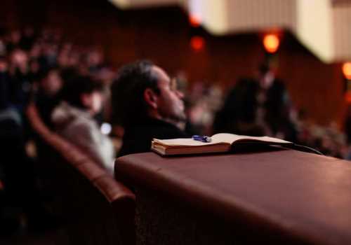 Man sat in a seminar with a book in the foreground