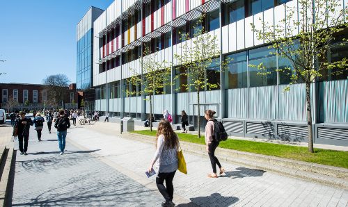 People walking alongside building on campus