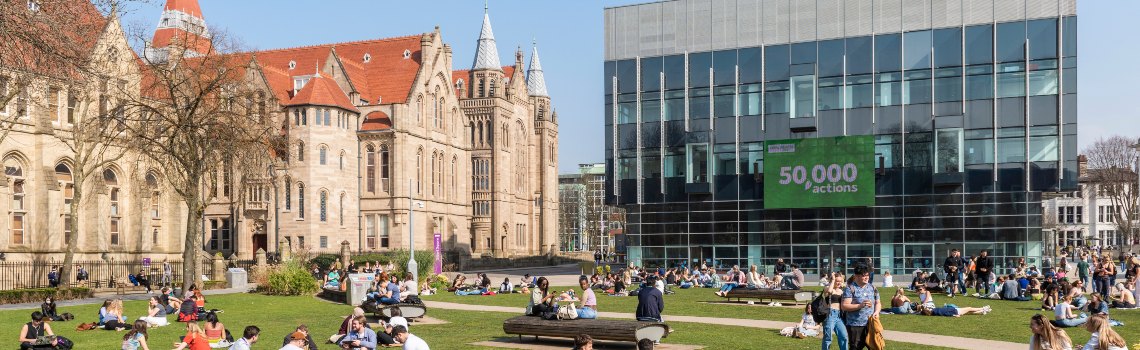 People sat on  grass outside a university building 