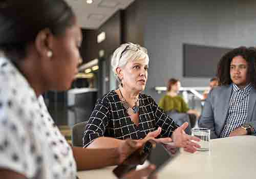 Women talking to a group in a conference setting 