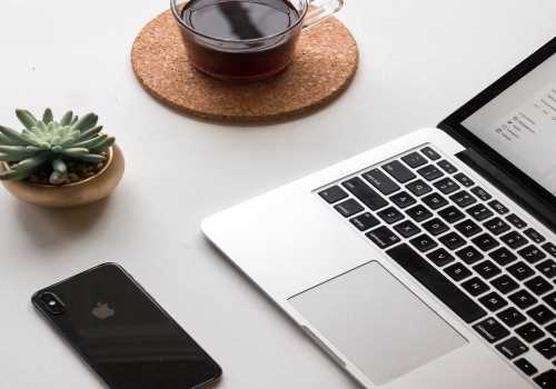 Table with a laptop, plant, phone and coffee set out