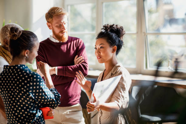 Four people have a standing meeting in an office space