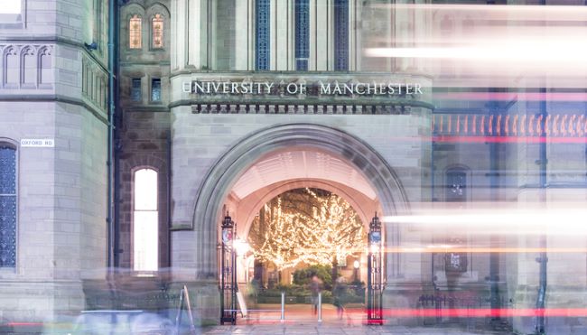 University of Manchester arch with lit up trees showing through