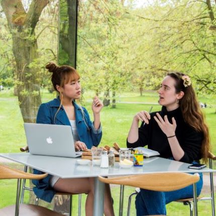 2 women talking at a cafe table in front of Whitworth park