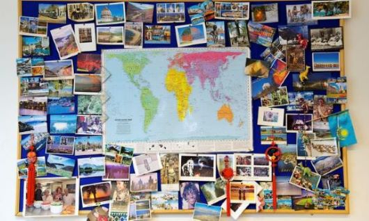 A world map surrounded by colourful postcards from around the world.